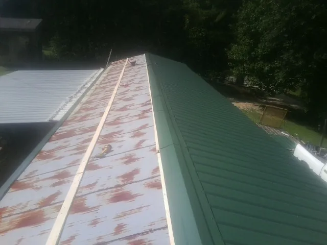 Old rusted panels beside newly installed green metal roofing — Wind Damage Roof Repair by Roofing Brothers in Kingston